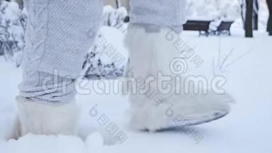 一个年轻女孩的腿在雪地里穿着高靴、毛毡靴gg靴子在雪地里行走。 一个下雪的冬季公园。 特写